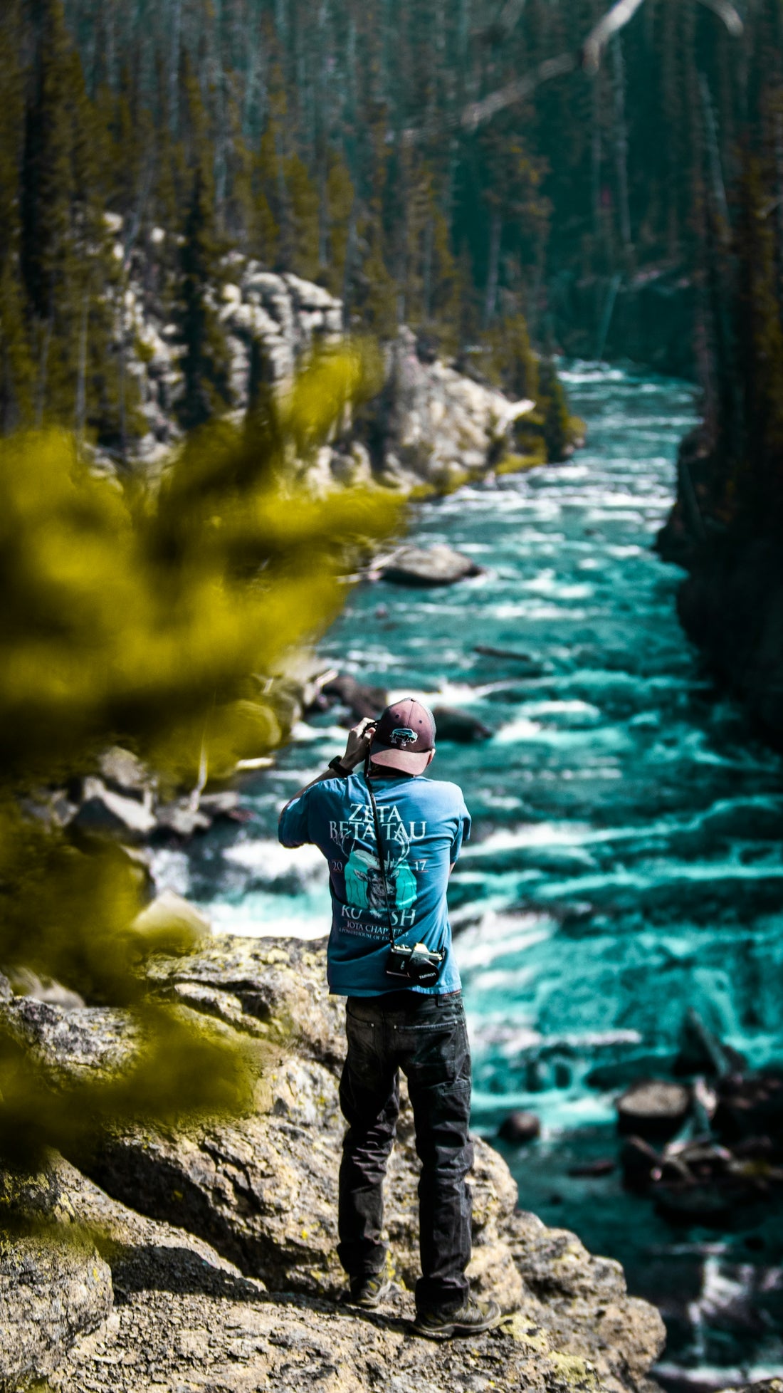 man in blue jacket standing on rock near river during daytime