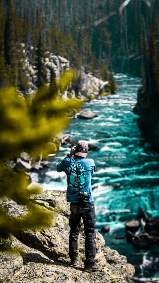 man in blue jacket standing on rock near river during daytime