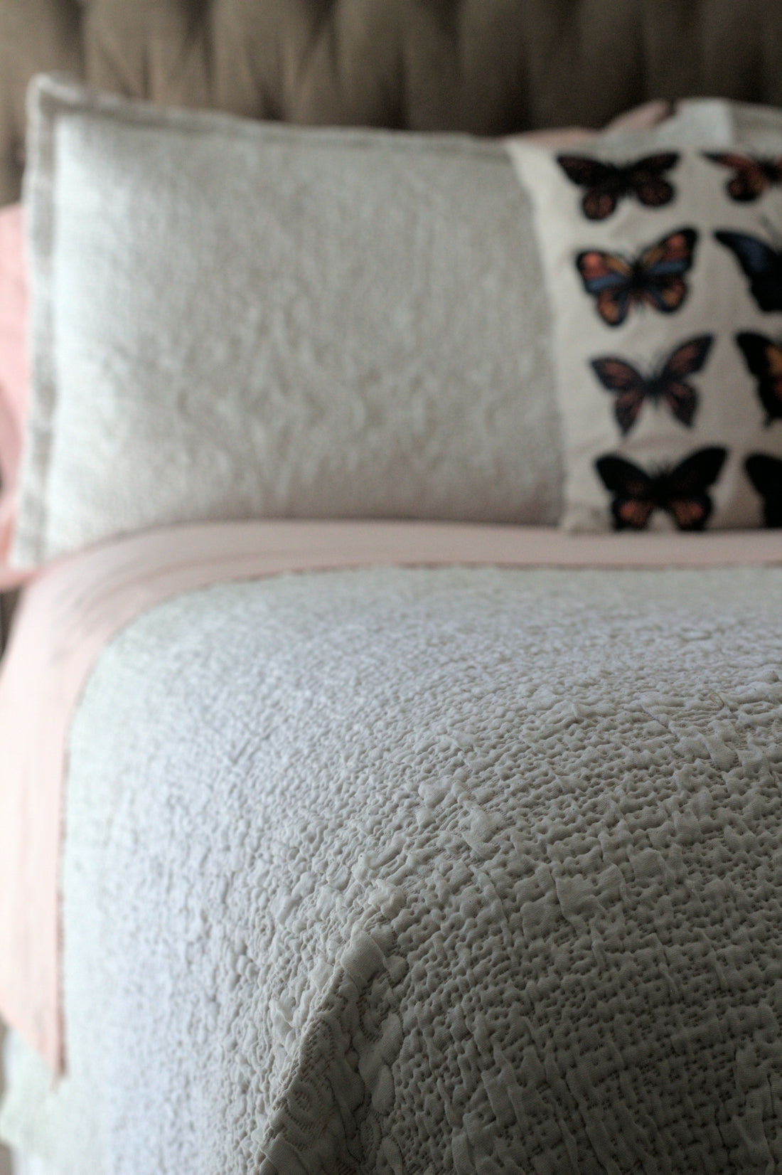 A bed with a white and pink comforter and pillows