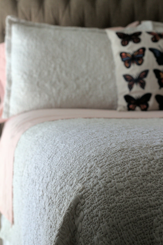 A bed with a white and pink comforter and pillows