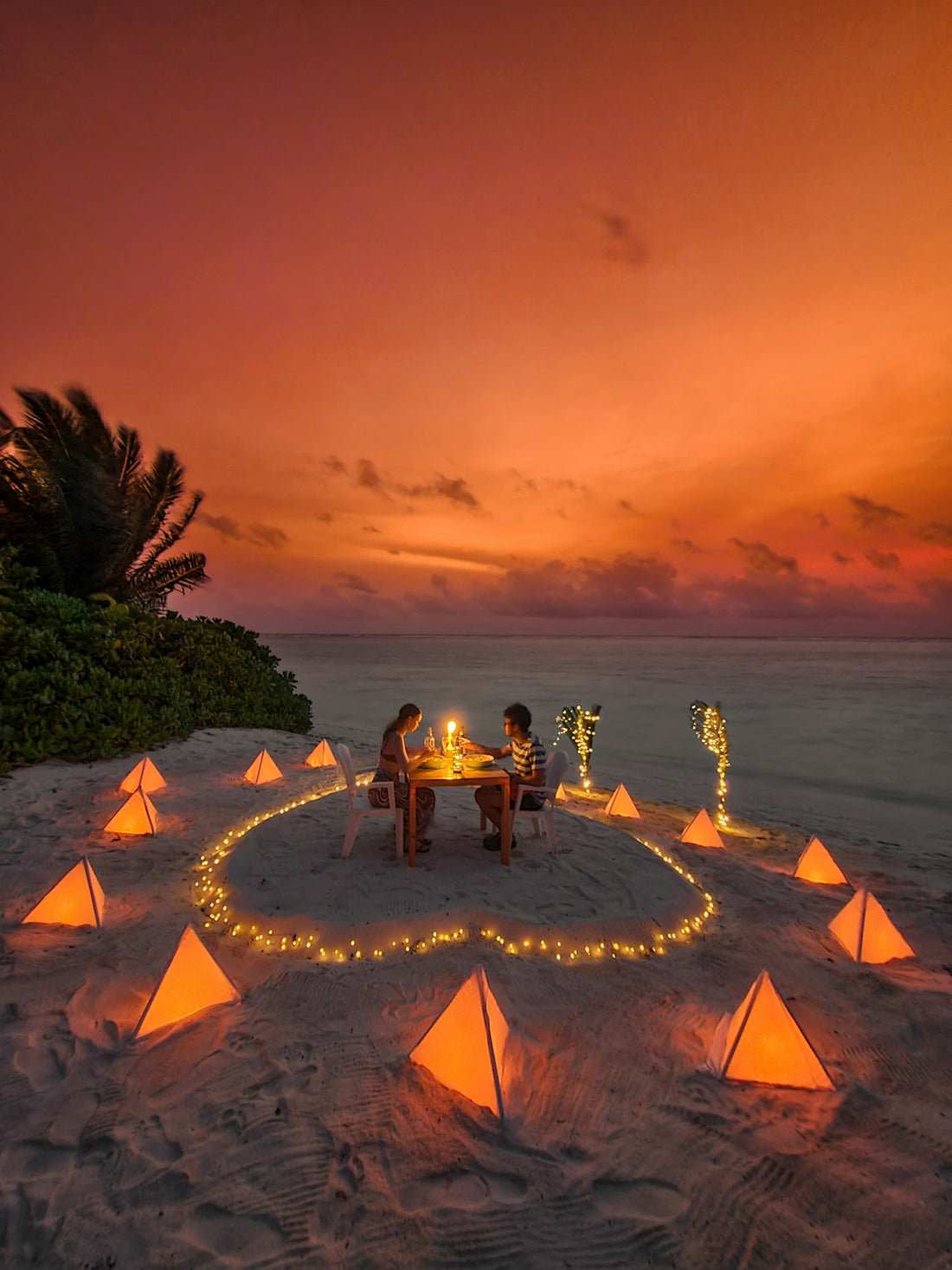 Couple having romantic dinner on beach at sunset.