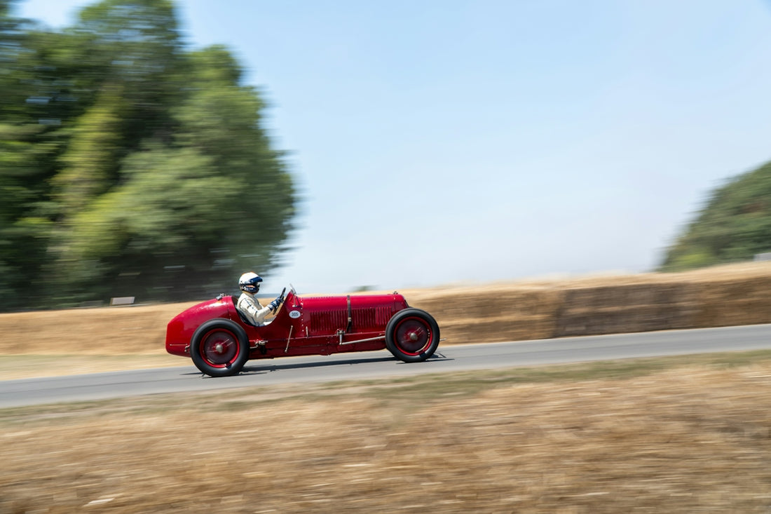 Red vintage race car speeding down a track
