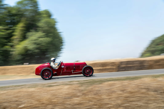 Red vintage race car speeding down a track