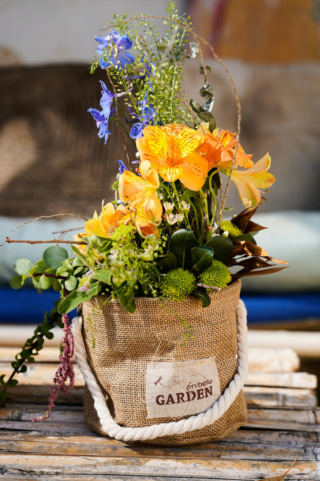 Beautiful orange and blue flowers in a burlap garden pot.