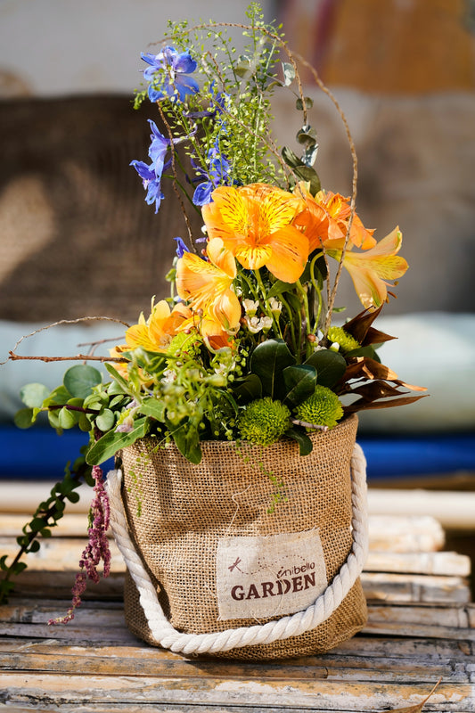 Beautiful orange and blue flowers in a burlap garden pot.